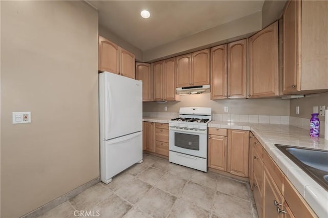 kitchen featuring light brown cabinetry, sink, and white appliances