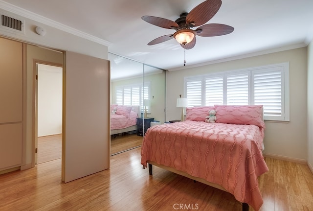 bedroom with ceiling fan, light hardwood / wood-style floors, ornamental molding, a closet, and multiple windows