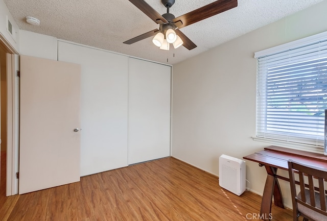 unfurnished bedroom with ceiling fan, light hardwood / wood-style flooring, a closet, and multiple windows