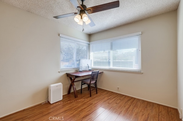 home office featuring hardwood / wood-style floors, a textured ceiling, ceiling fan, and a wealth of natural light