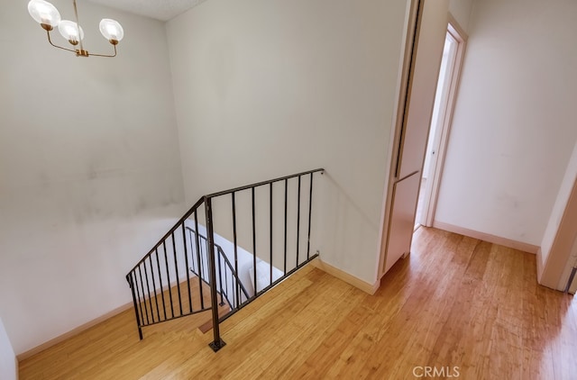 stairway featuring wood-type flooring and a chandelier