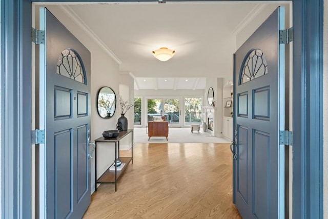 foyer featuring beam ceiling, crown molding, and light hardwood / wood-style floors