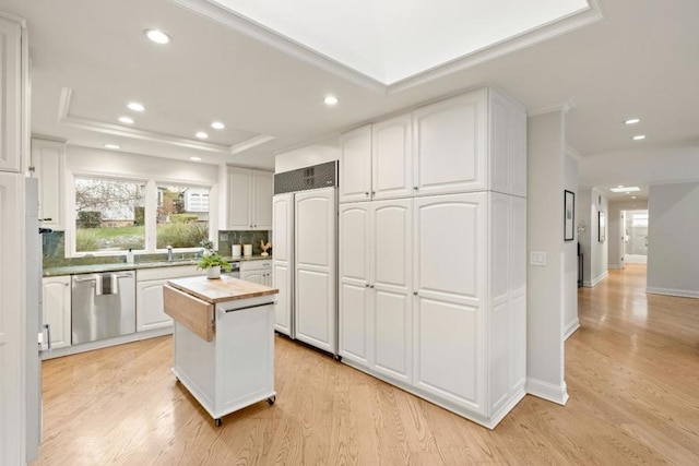 kitchen featuring backsplash, white cabinetry, dishwasher, and a raised ceiling