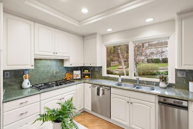 kitchen with white cabinets, stainless steel appliances, sink, a tray ceiling, and crown molding