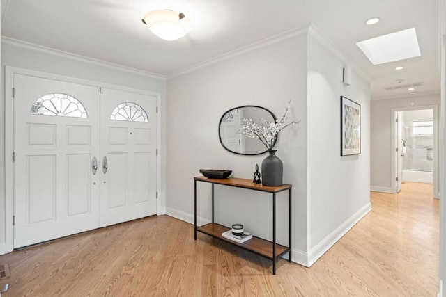 foyer entrance with a skylight, ornamental molding, and light hardwood / wood-style floors