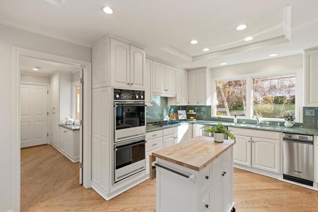 kitchen featuring a kitchen island, white double oven, decorative backsplash, sink, and white cabinetry