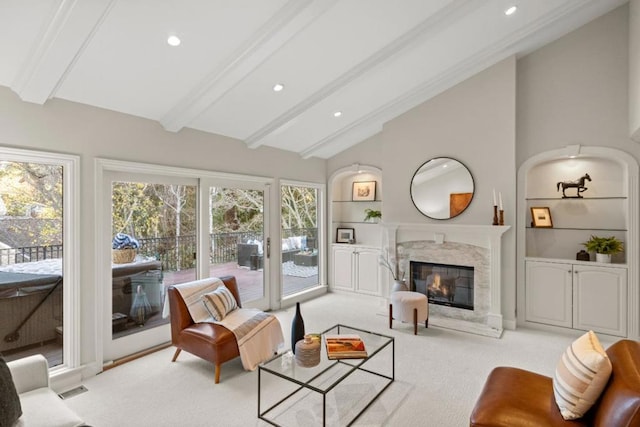 carpeted living room with vaulted ceiling with beams, built in features, and a fireplace