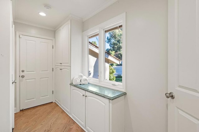 doorway with ornamental molding and light hardwood / wood-style flooring