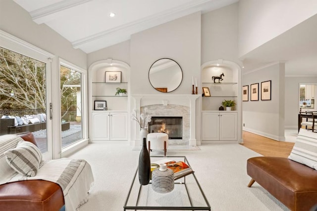 carpeted living room featuring crown molding, a fireplace, lofted ceiling with beams, and built in shelves