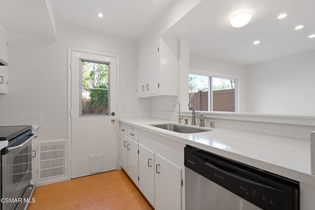 kitchen featuring appliances with stainless steel finishes, light hardwood / wood-style flooring, white cabinets, and sink