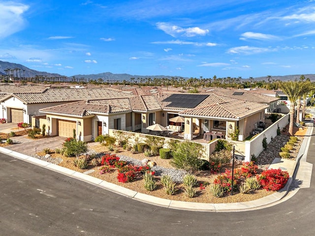 view of front facade with solar panels, a garage, and a mountain view