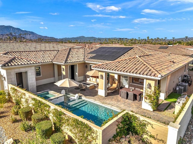 rear view of house featuring a pool with hot tub, a patio, central AC unit, and a mountain view