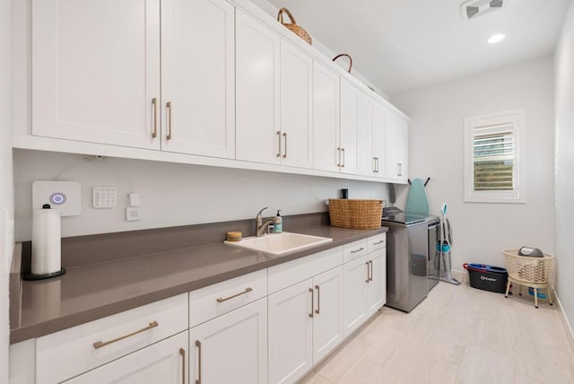 laundry room with cabinets, washing machine and clothes dryer, and sink