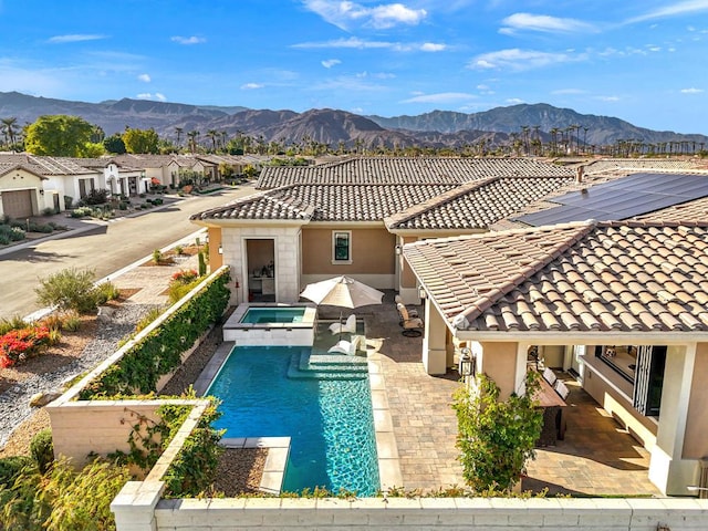 rear view of house with a pool with hot tub, a patio area, and a mountain view