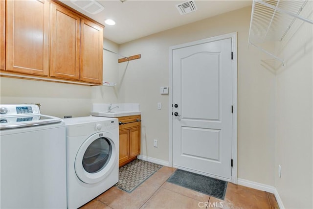 laundry room with washing machine and dryer, cabinets, and light tile patterned floors