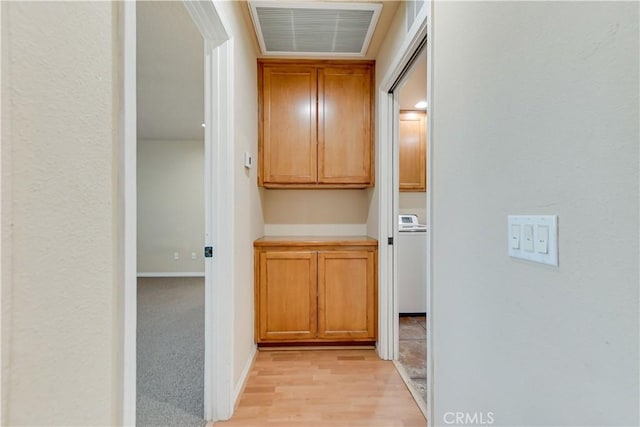 hall with washer / dryer and light hardwood / wood-style floors