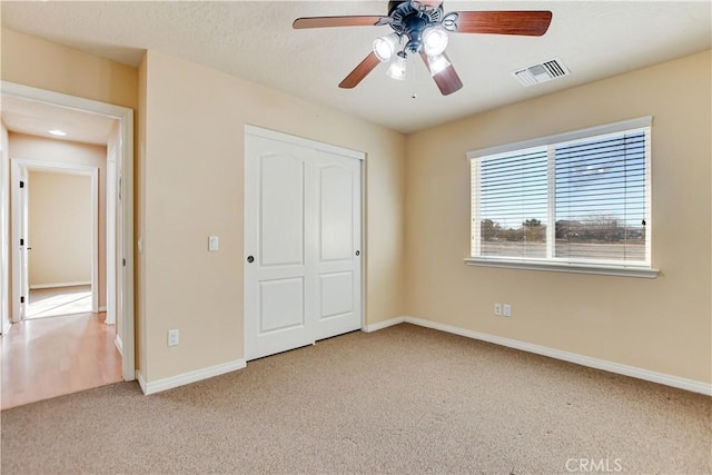 unfurnished bedroom featuring a closet, ceiling fan, and light colored carpet