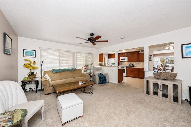 living room featuring ceiling fan, a wealth of natural light, and light carpet