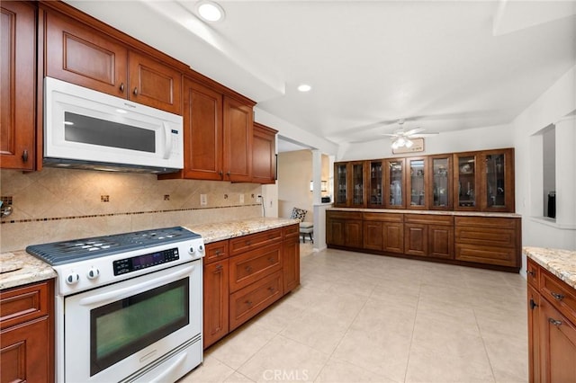 kitchen with ceiling fan, decorative backsplash, range with gas stovetop, and light stone countertops