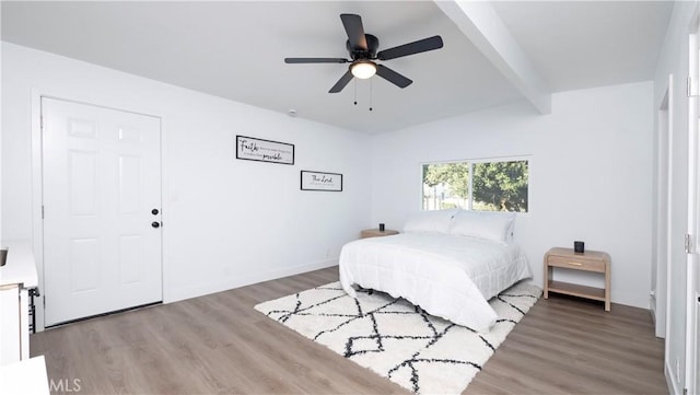 bedroom with ceiling fan, hardwood / wood-style floors, and beam ceiling