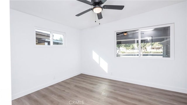 spare room featuring ceiling fan, wood-type flooring, and a wealth of natural light