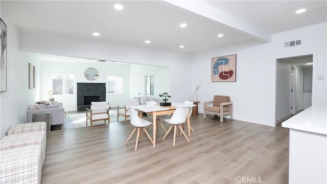 dining room featuring light wood-type flooring, ceiling fan, and beam ceiling