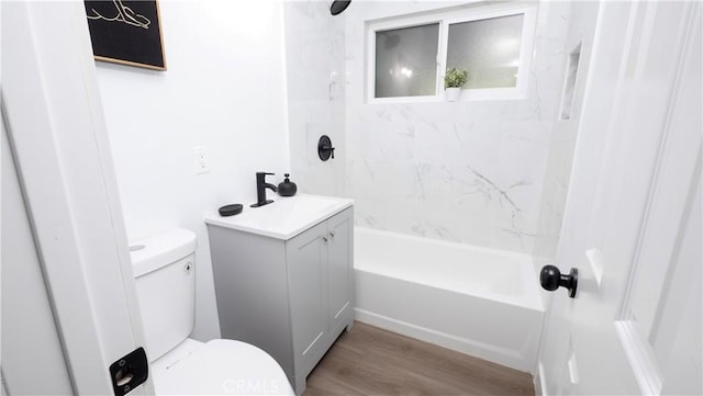 full bathroom featuring toilet, tiled shower / bath, wood-type flooring, and vanity