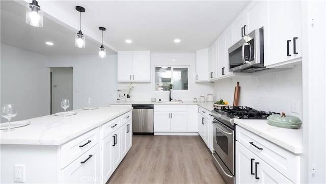 kitchen featuring light wood-type flooring, light stone counters, stainless steel appliances, and white cabinetry