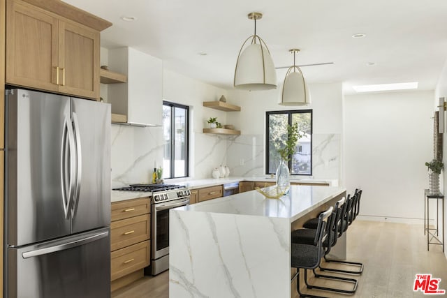 kitchen with pendant lighting, stainless steel appliances, backsplash, light hardwood / wood-style flooring, and a breakfast bar area