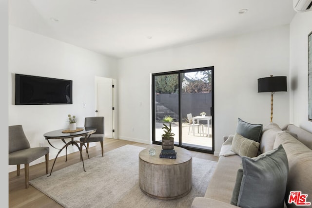 living room with an AC wall unit and light hardwood / wood-style flooring