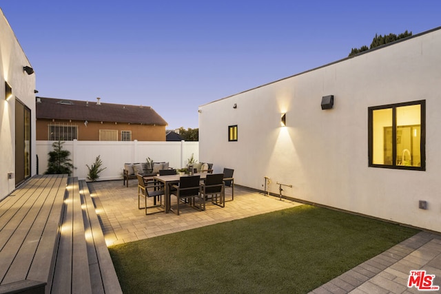 deck at dusk featuring a patio area and a yard