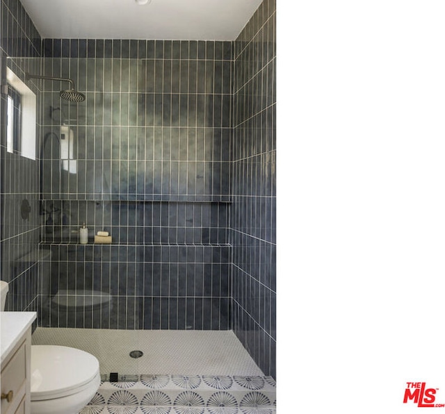 bathroom featuring toilet, vanity, tile patterned floors, and a tile shower