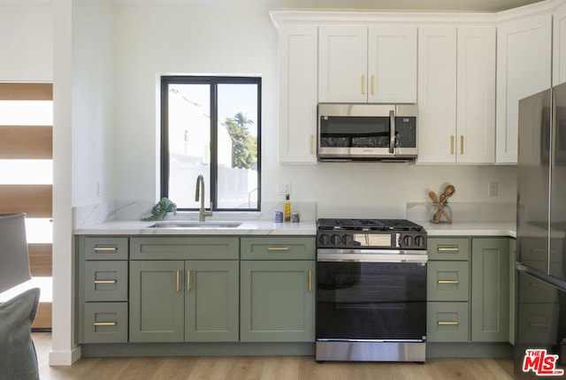 kitchen featuring green cabinetry, white cabinets, sink, and stainless steel appliances