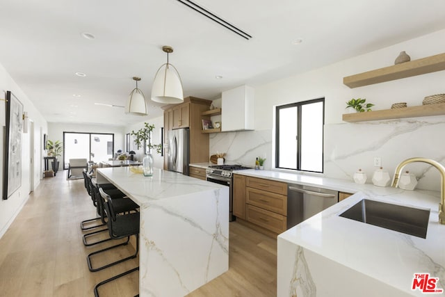 kitchen featuring light stone countertops, white cabinets, appliances with stainless steel finishes, sink, and hanging light fixtures