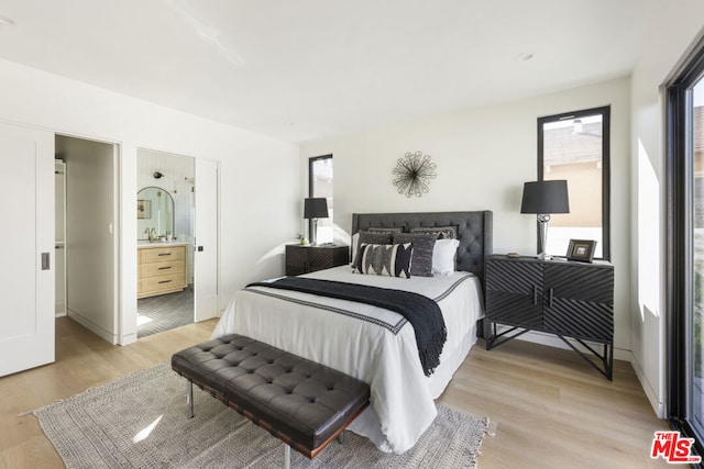 bedroom with light hardwood / wood-style flooring and ensuite bath