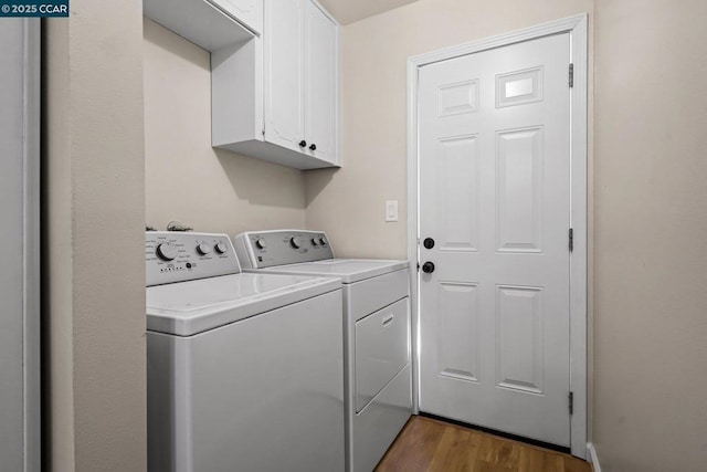 clothes washing area featuring dark hardwood / wood-style flooring, cabinets, and independent washer and dryer