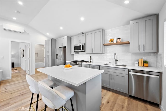 kitchen with a center island, stainless steel appliances, sink, a wall unit AC, and a breakfast bar