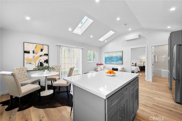 kitchen featuring a wall mounted AC, a center island, stainless steel refrigerator, light hardwood / wood-style flooring, and gray cabinetry