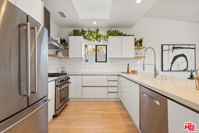 kitchen featuring a skylight, white cabinetry, light hardwood / wood-style floors, premium appliances, and sink