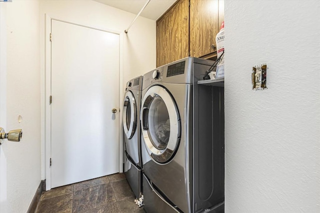 clothes washing area featuring separate washer and dryer and cabinets