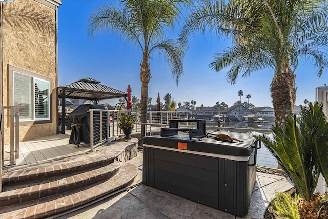 view of patio featuring a gazebo, a hot tub, and a water view