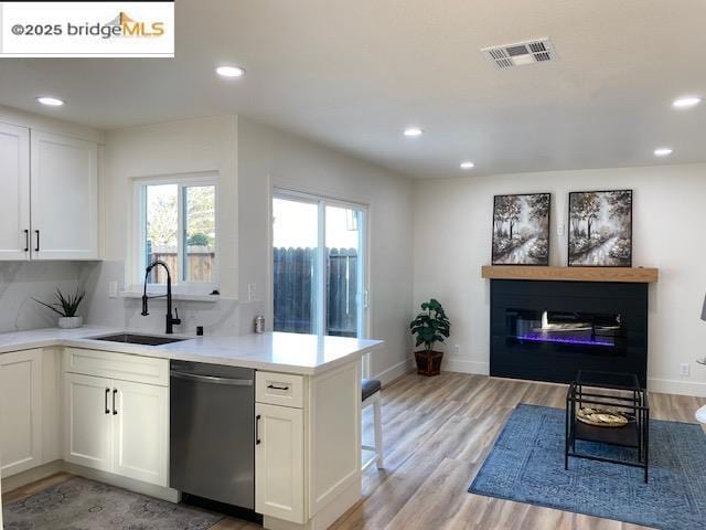 kitchen featuring sink, light hardwood / wood-style floors, white cabinetry, and dishwasher