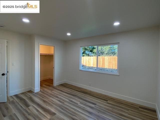 unfurnished bedroom with a walk in closet, a closet, and hardwood / wood-style flooring