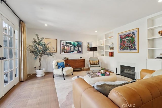 living room with built in shelves and light hardwood / wood-style flooring