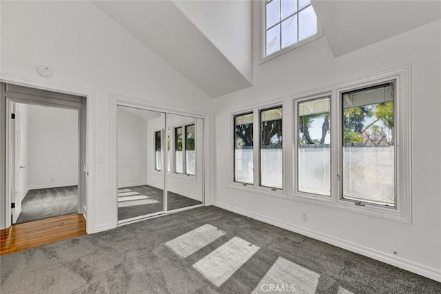 interior space featuring a high ceiling, a closet, and dark carpet