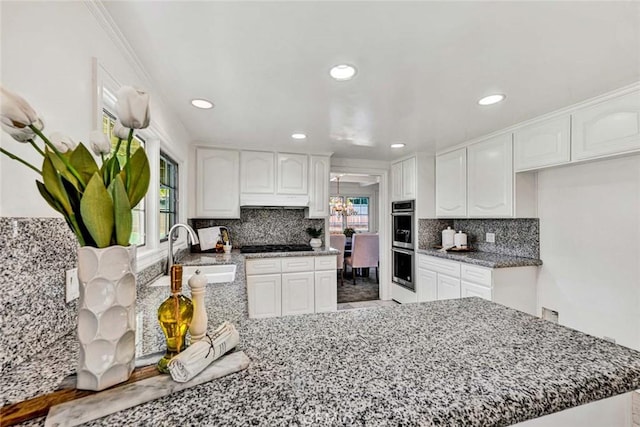 kitchen with white cabinets, black gas cooktop, kitchen peninsula, and sink