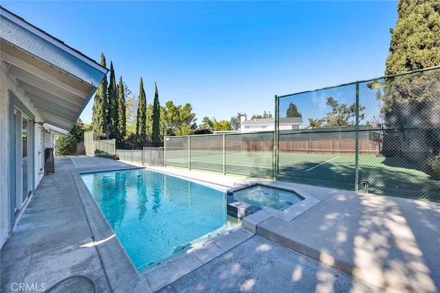 view of swimming pool featuring tennis court and an in ground hot tub