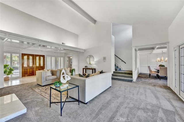 living room with a towering ceiling, carpet floors, a chandelier, and beamed ceiling