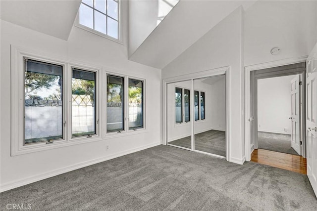 unfurnished bedroom featuring high vaulted ceiling, carpet flooring, and a closet