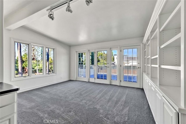 unfurnished living room with french doors, dark carpet, rail lighting, and plenty of natural light